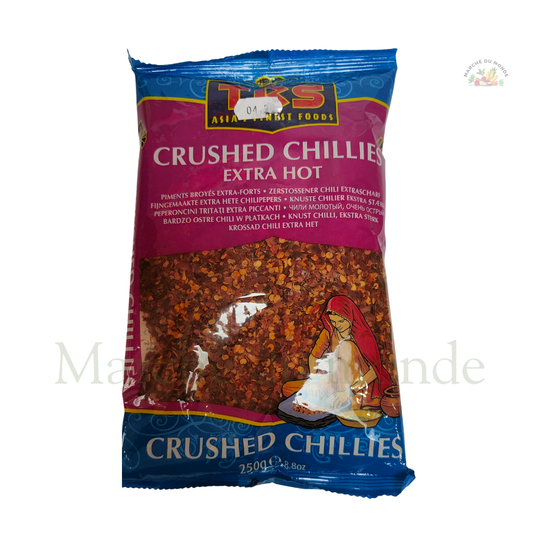 Sachet d'épices TRS "Crushed Chillies Extra Hot" de couleur rose et bleue. L'emballage transparent montre des flocons de piment rouge séchés.
